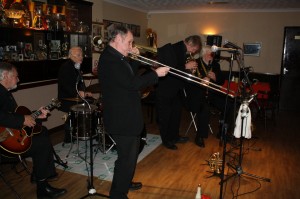 Laurie Chescoe's Reunion Band at Farnborough Jazz Club, Kent, UK on 14th November 2014. With Laurie (drm, ALAN (‘Lord Arsenal’) BRADLEY (trp/p/voc), JOHN LEE (rds), MIKE POINTON (trb/voc), COLIN BRAY (p/sop-sax/xylo), JIM DOUGLAS (bj/gtr) & PETER SKIVINGTON (b-gtr/b-uke). Photo by Mike Witt.