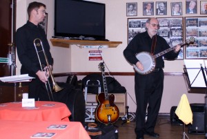 John Stewart takes a solo, whilst Bill Todd (tromb) looks on. Phoenix Dixieland Jazz Band on 23Jan2015 at Farnborough Jazz Club in Kent. Photo by Mike Witt.