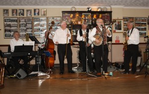 Nick Singer sings 'Ace In The Hole'. BOB DWYER'S BIX & PIECES at Farnborough Jazz Club on 1st May 2015. With BOB (tromb&voc) MAX EMMONS (trump), BERNIE HOLDEN (clar&sax), CHRIS NEWMAN (piano), JOHN BAYNE (d.bass &b.sax), NICK SINGER bnj&voc) and LAURIE CHESCOE (drms). Photo by Mike Witt.