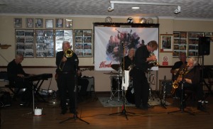 Laurie Chescoe's Reunion Jazz Band at Farnborough Jazz Club on 3rd july 2015. (LtoR) Colin Bray (piano&alto sax) Jackie Free (trmb), (hidden) Jim Douglas (bnjo&guitar), Laurie Chescoe (drms), Alan (‘Lord Arsenal’) Bradley (trmpt &piano),Peter Skivington (bass guitar/bass Ukelele), John Lee (clnt/tenor sax). Photo by Mike Witt.3jul2015
