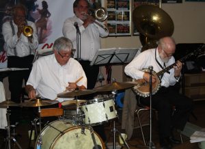 Band leader Dave Rance (1st trumpet &vocals), plus Pete Lay (drums), Graham Wiseman (trombone),Graham Wiseman (trombone), John Arthy (hidden by his heavy tuba) and Nick Singer (banjo), 5 of the 8 musicians in the 'Yerba Buena Celebration Jazz Band' seen here at Farnborough Jazz Club (Kent) on 26th June 2016. Photo by Mike Witt.