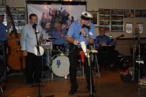 George singing with his George 'Kid' Tidiman's All Stars at Farnborough Jazz Club on 31st July 2015. (LtoR) hidden Tim Huskisson (cl), John Sirett (d.bass), Denny Islett (trp), Bill Finch (drms), George 'Kid' Tidiiman (trb) & 'Southend Bob' Allbut (bnj). Photo by Mike Witt.