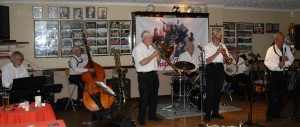 Bob Dwyer's Bix & Pieces at Farnborough JC, Kent 10Jul2015. Bob (trombone), Max Emmons (trumpet & harmonica), Bernie Holden (clarinet&alto sax), Laurie Chescoe (drums), John Bayne (d.bass& bass sax), John Stewart (banjo & guitar)& pianist Chris Newman. Photo by Mike Witt.