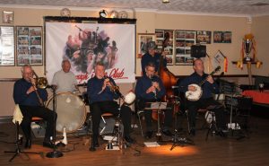 It's Halloween Party time. The guys are trying so hard to avoid our gaze. (LtoR) Roy Stokes (trombone), Pete Jackman (drums), Mike Scroxton (trumpet), Alan Cresswell (clarinet), Mike Broad (d.bass), & Kevin Scott (banjo) who are the Golden Eagle Jazz Band at Farnborough Jazz Club on 30th October 2016. Photo taken by Mike Witt.