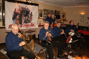 It's still Halloween Party time. The guys are still trying so hard to avoid our gaze. (LtoR) Roy Stokes (trombone), Pete Jackman (drums), Mike Scroxton (trumpet), Mike Broad (d.bass), Alan Cresswell (clarinet) & Kevin Scott (banjo) who are the Golden Eagle Jazz Band at Farnborough Jazz Club on 30th October 2016. (LtoR) Photo taken by Mike Witt.