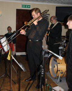 Bill Todd takes a solo for Phoenix Dixieland Jazz Band at Farnborough Jazz Club on 23rd October 2015. (LtoR) Bill Todd (trombone), John Stuart (banjo) and Paul Higgs (trumpet). Photo by Mike Witt.