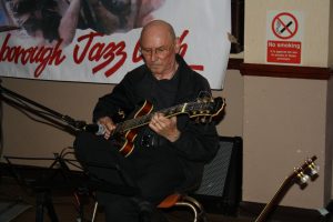 Johnny McCallum plays guitar for 'Bill Phelan's Muscrat Ramblers' at Farnborough Jazz Club on 27th May 2016. Photo by Mike Witt.