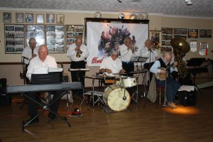 Yerba Buena Celebration Jazz Band at Farnborough Jazz Club (Kent) on 3rd June 2016. (LtoR) Brian White (clarinet), Hugh Crozier (piano), Mike Barry (2nd trumpet&vocals), Pete Lay (drums), Dave Rance (1st trumpet&vocals), George 'Kid' Tidiman (trombone), Nick Singer (banjo &vocals) & John Arthy (tuba). Photo by Mike Witt.