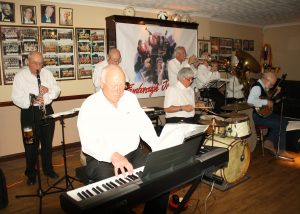 Yerba Buena Celebration Jazz Band at Farnborough Jazz Club (Kent) on 3rd June 2016. (LtoR) Brian White (clarinet), Hugh Crozier (piano), Mike Barry (2nd trumpet &vocals), Pete Lay (drums), Dave Rance (1st trumpet &vocals), George 'Kid' Tidiman (trombone), John Arthy (tuba) & Nick Singer (banjo &vocals). Photo by Mike Witt.