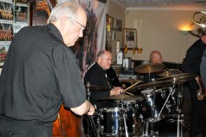 The 'Engine' of Tony Pitt's All Stars play for Keith Grant's birthday (co-promoter of Farnborough Jazz Club) on 12th August 2016. (LtoR) Andy Lawrence (double bass), John Ellmer (drums) & Tony Pitt (banjo). Photo by Mike Witt (also a b'day boy).